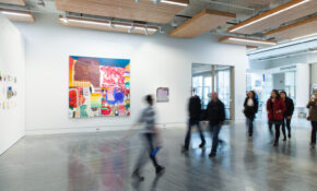 A colourful painting on display in Emily Carr University's exhibition commons, with people walking by in the foreground.