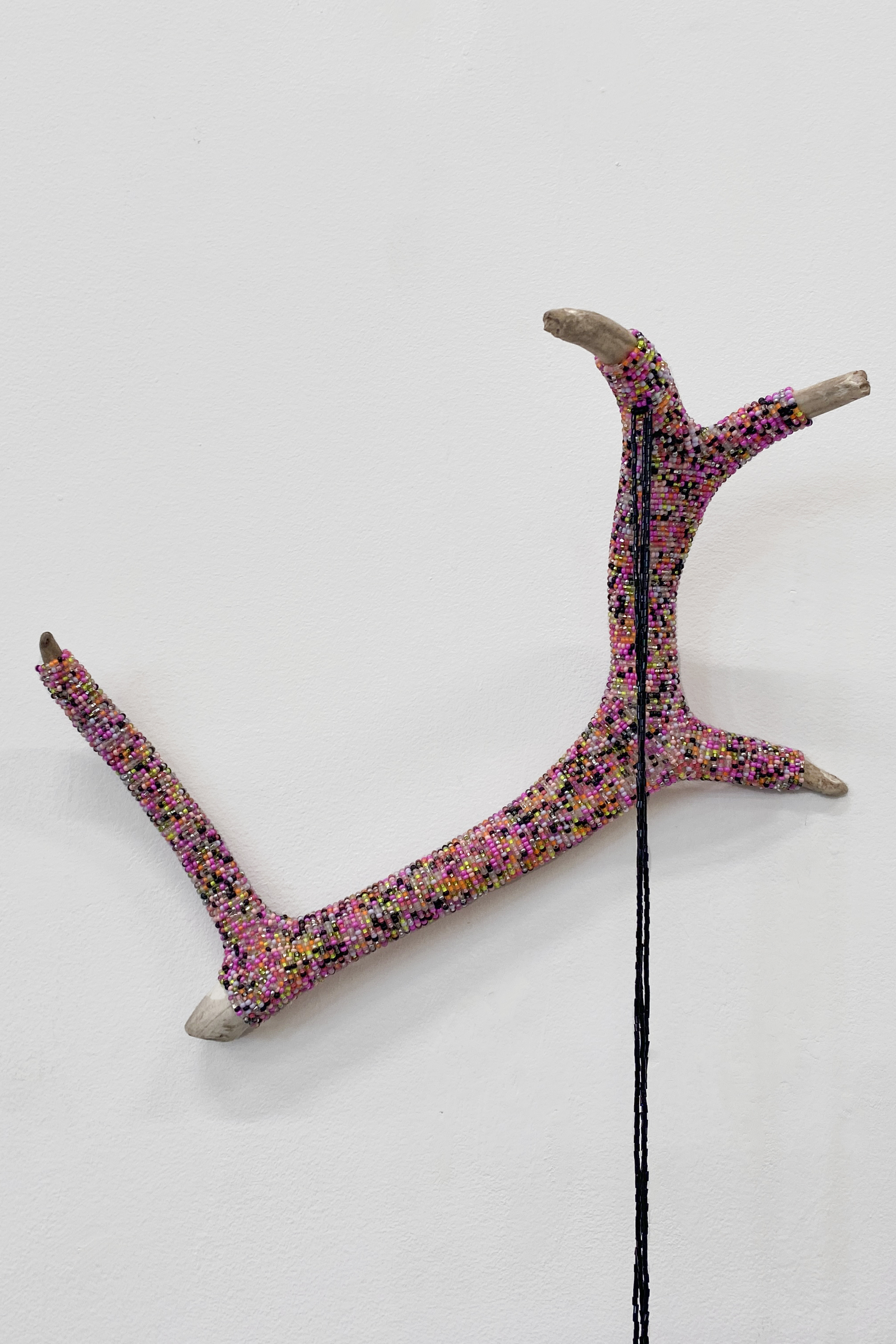 A caribou antler wrapped in colourful beading with a black beaded thread hanging down