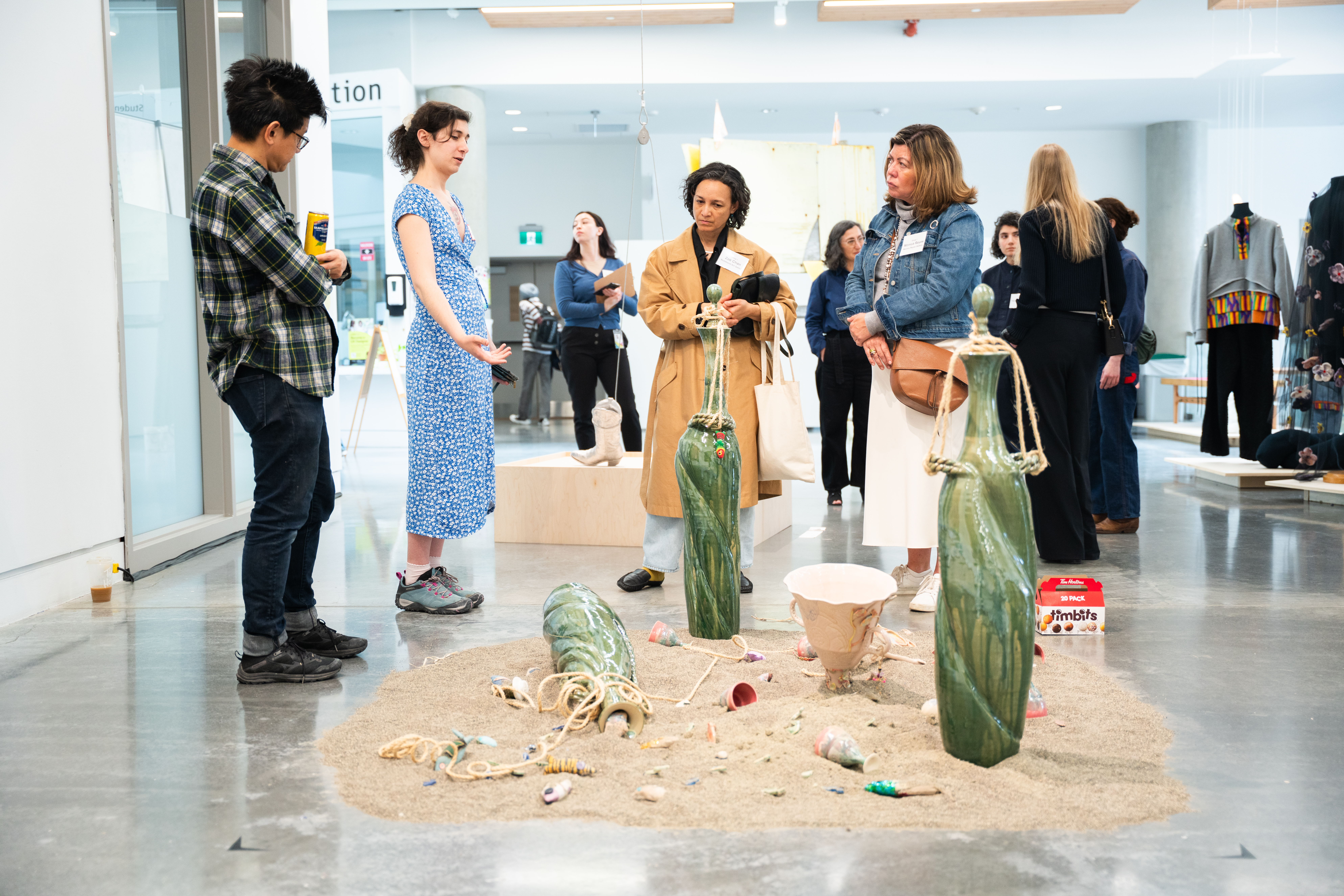 A group of four people look down at an artwork on the lower ground with sand