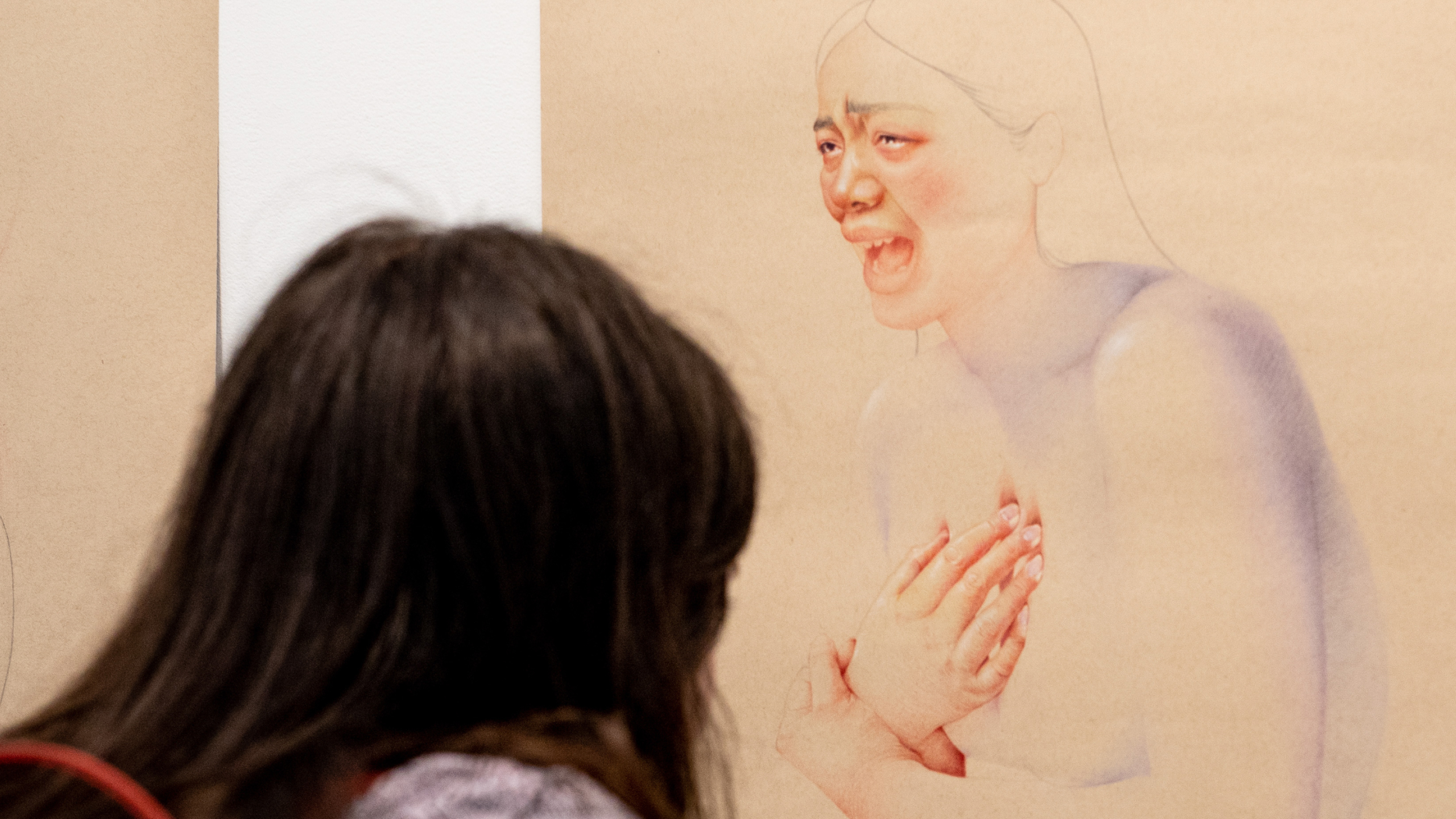 A person looks closely at an illustration of a crying woman.