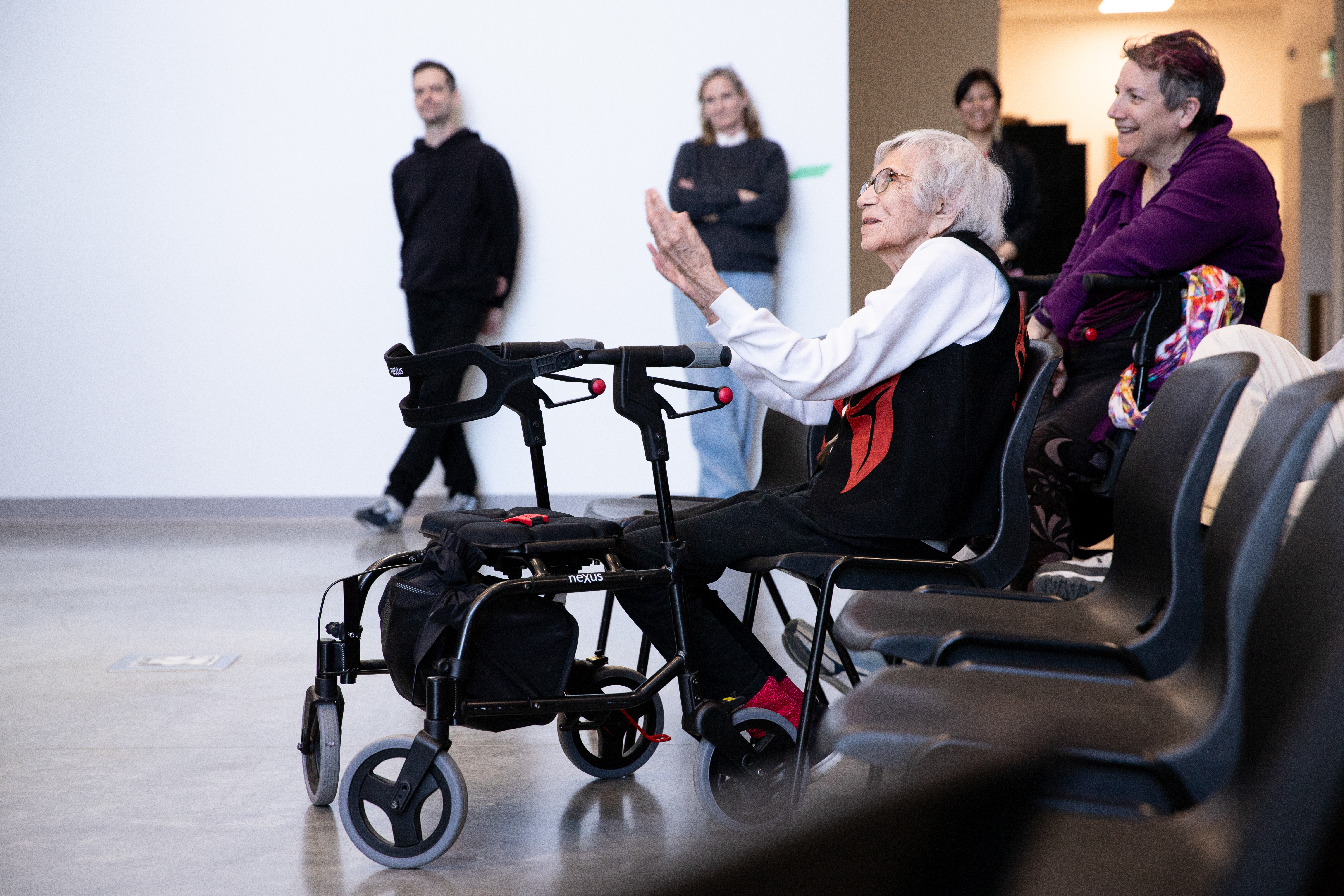 An elderly woman sits in a wheelchair sits in the front