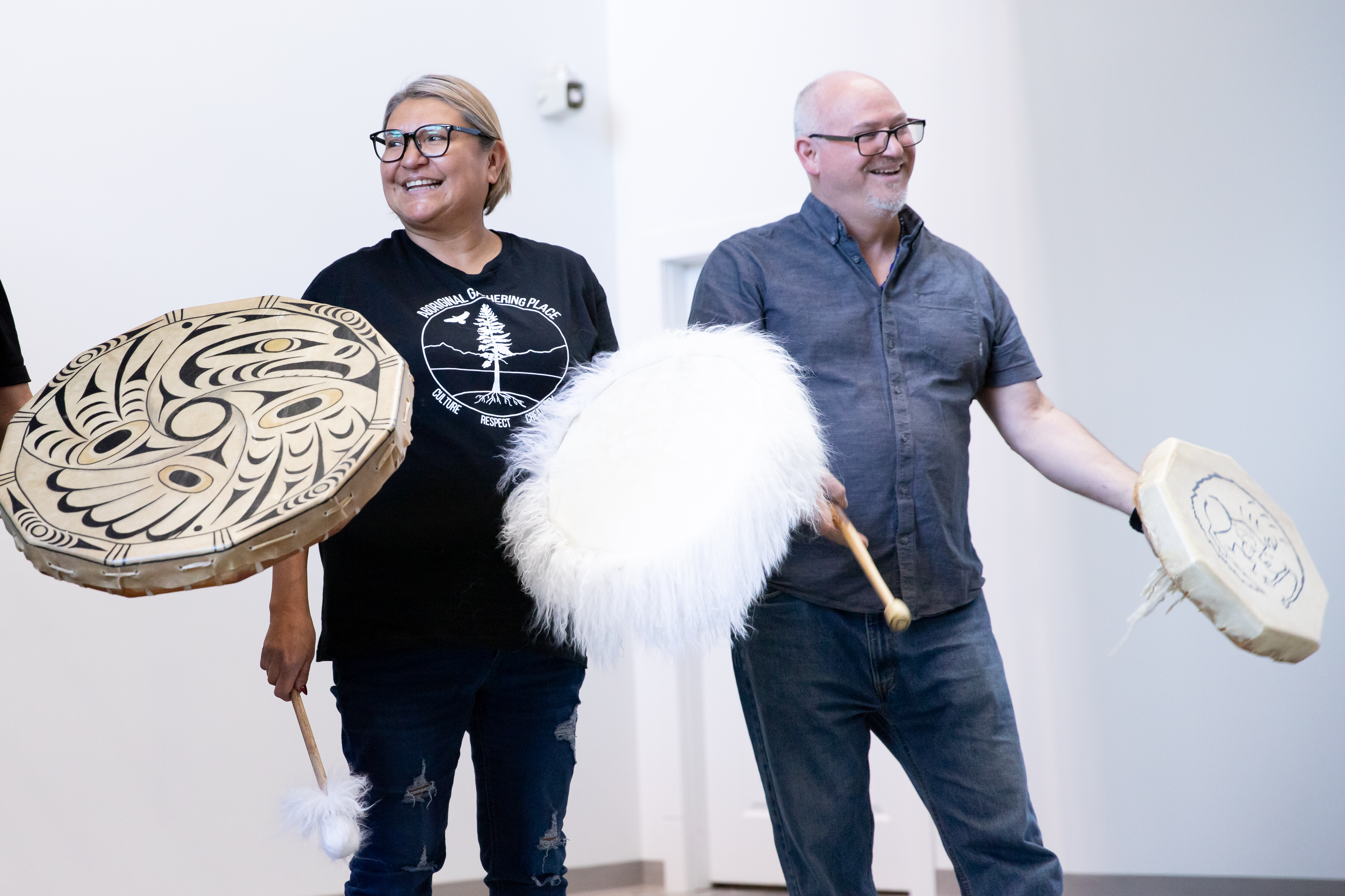 A woman and man with drums stand together in front of a crowd