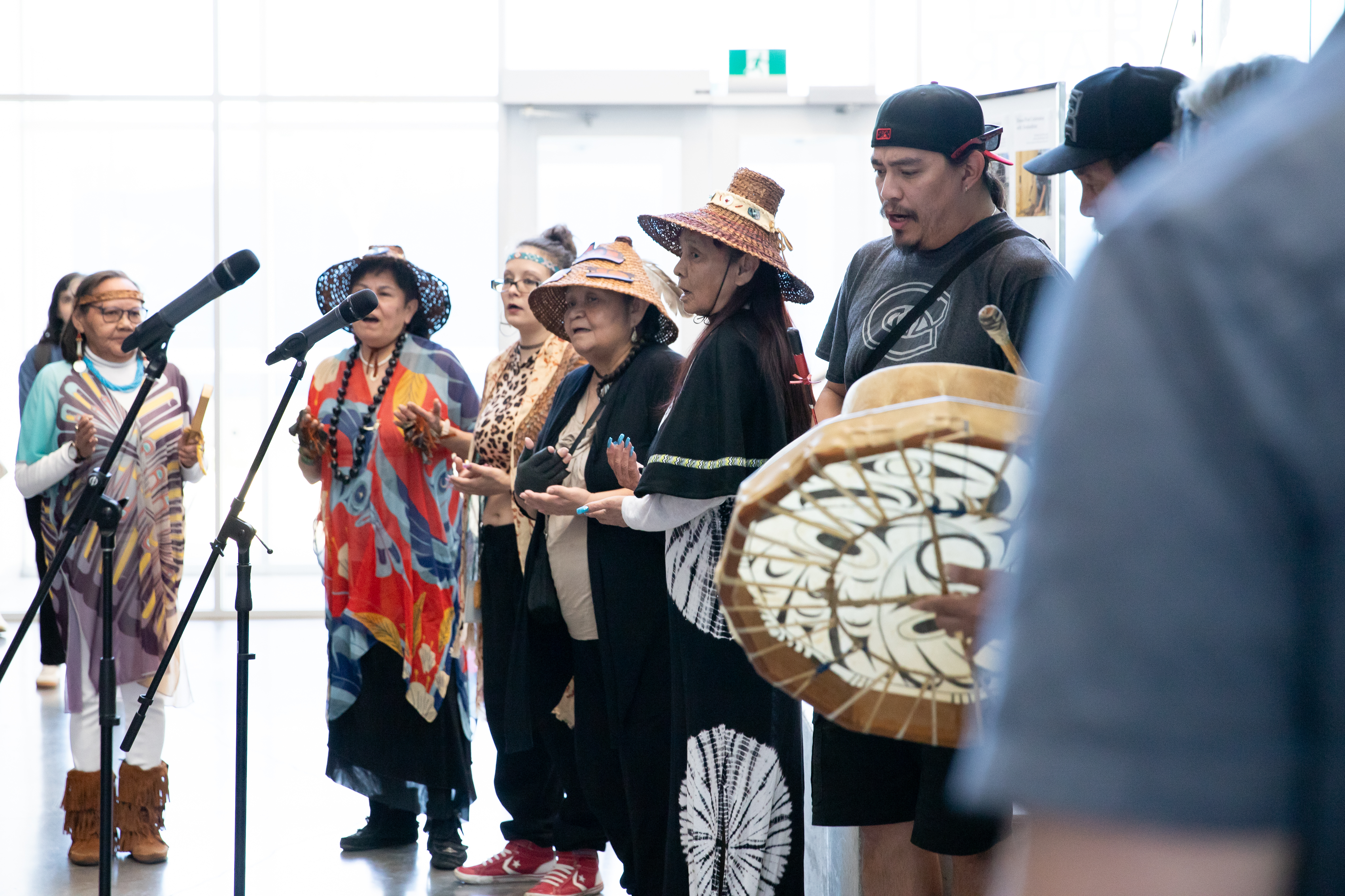 A crowds of men and women at the microphones with drums in their hands