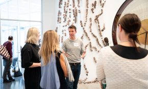 A group of four people discuss an artwork