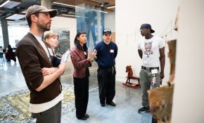 A group of five people look at an artwork