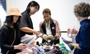 A group of people are looking at a pile of shoes on a table.
