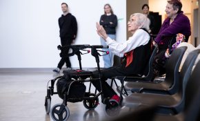 An elderly woman sits in a wheelchair sits in the front