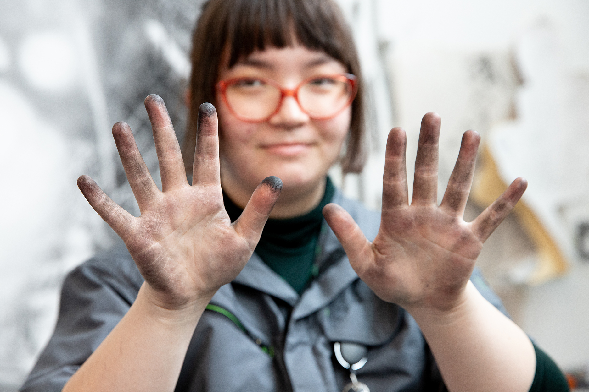 A person holds up hands stained with charcoal.