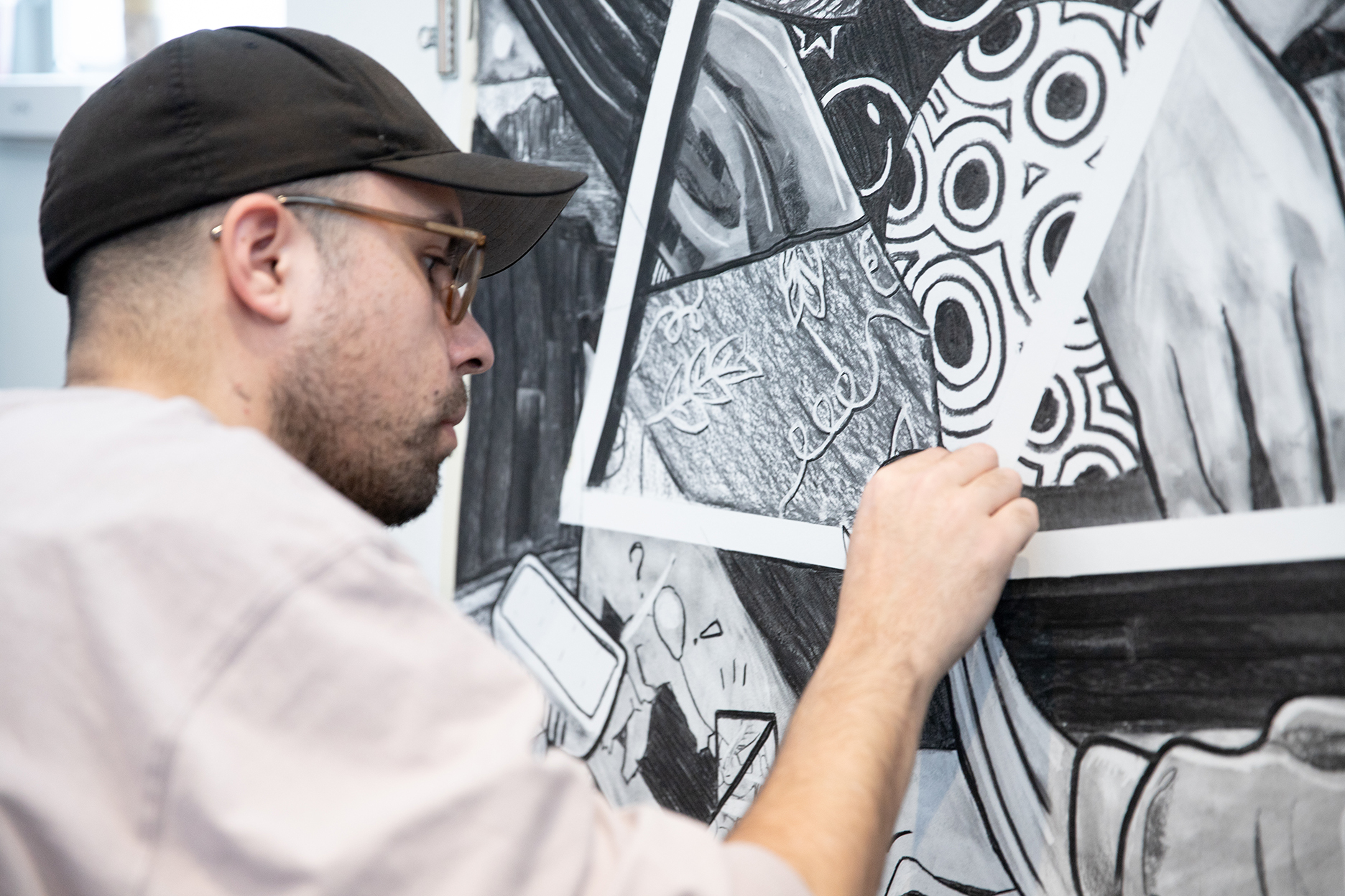 A person works in close-up on a large-scale black-and-white drawing.