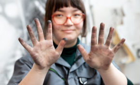 A person holds up hands stained with charcoal.